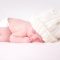 17348374 - a newborn baby is wearing a white hat and laying down sleeping on a soft white background
