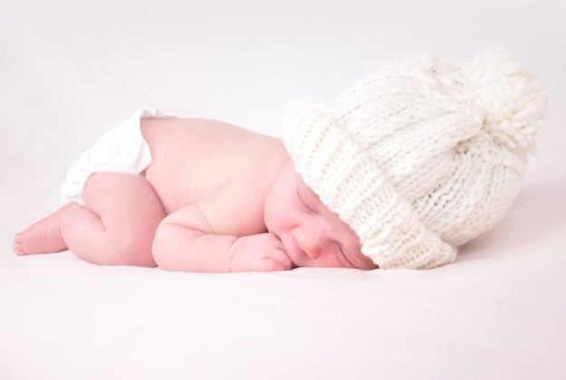 esophagus 17348374 - a newborn baby is wearing a white hat and laying down sleeping on a soft white background